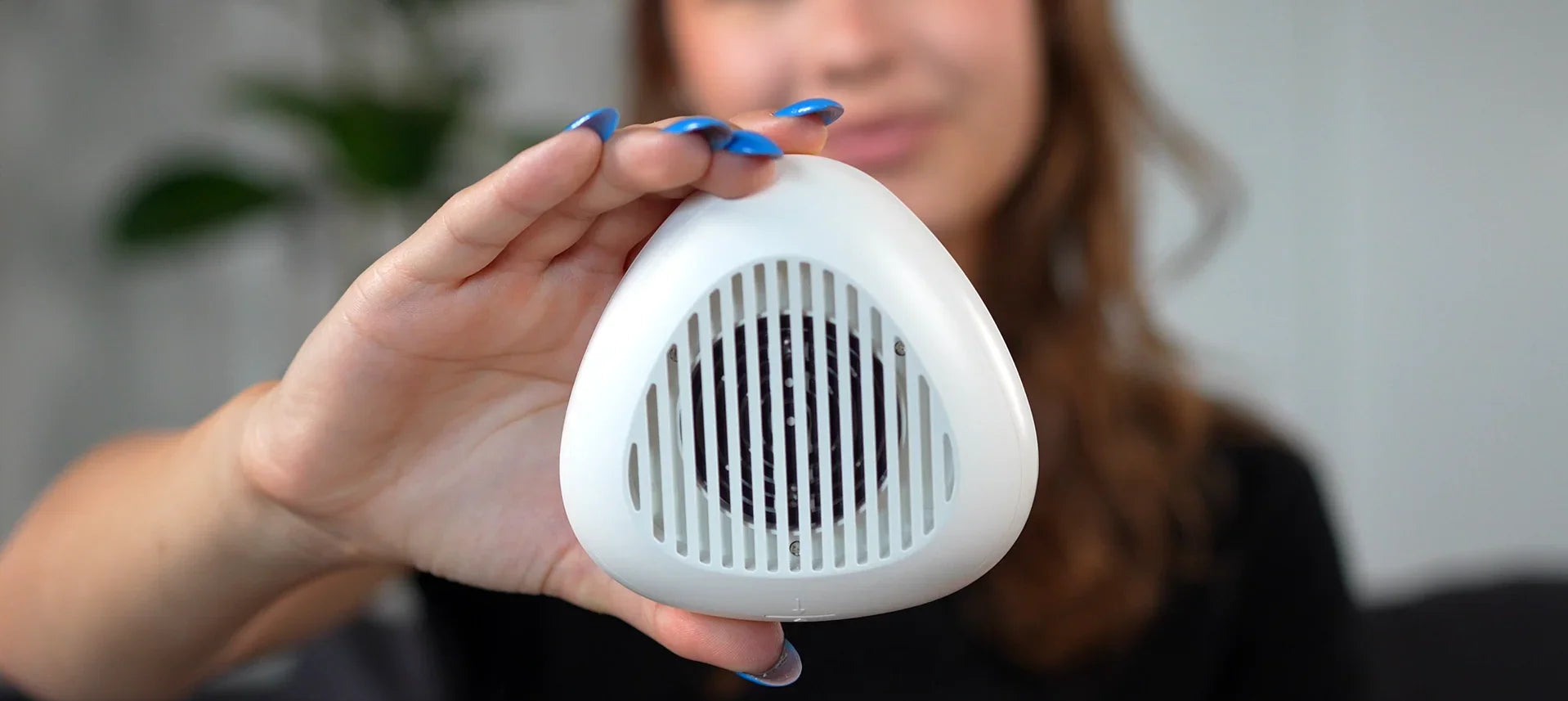 Person holding a white triangular device lipaw with a blurred background